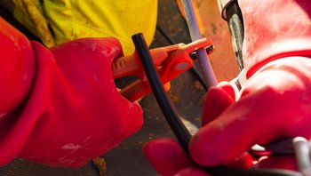 Hand in Handshcuh arbeitet im Stromnetz