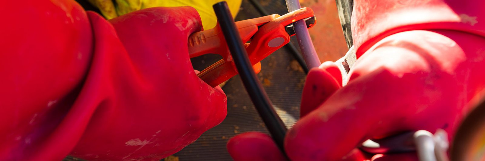 Hände in Schutzhandschuhen im Stromnetz