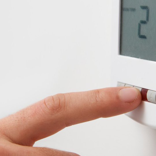 Finger auf der Heizungssteuerung